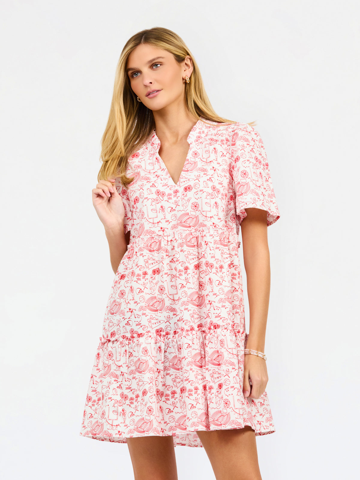 A woman modeling a short-sleeve red and white dress with a V-neckline and tiered skirt against a plain white studio background.