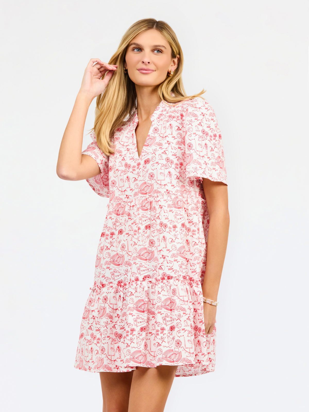 A woman modeling a short-sleeve red and white dress with a V-neckline and tiered skirt against a plain white studio background.