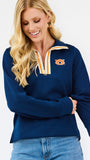A woman wearing a navy blue textured quarter-zip sweatshirt with a white and gold striped collar and an Auburn Tigers logo on the chest, paired with blue jeans against a white studio background.