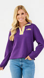 A woman wearing a purple LSU quarter-zip pullover sweater with yellow trim and blue jeans, photographed against a clean white studio background.