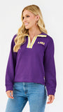 A woman wearing a purple LSU quarter-zip pullover sweatshirt with yellow and white trim, paired with blue jeans, against a plain white studio background.