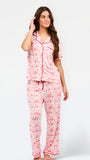 A woman modeling a two-piece pajama set featuring a short-sleeve button-front top and matching pants, red toile print with red piping and a red drawstring waist.