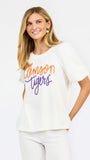 A woman wearing a white short-sleeve t-shirt with 'Clemson Tigers' printed in orange and purple script across the chest, paired with white pants, against a plain white background.
