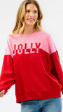 A woman wearing a color-blocked crewneck sweatshirt with a pink upper section and red lower section, featuring the word 'JOLLY' printed in white across the chest, paired with blue jeans against a plain white background.