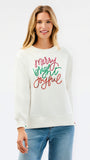 A woman wearing a cream-colored crewneck sweatshirt with 'Merry Bright Joyful' written in red and green cursive text on the front, paired with blue jeans, against a plain white background.