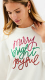 A woman wearing a cream-colored crewneck sweatshirt with 'Merry Bright Joyful' written in red and green glitter-style lettering on the front, paired with blue jeans, against a plain white studio background.