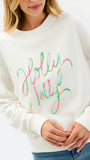 A woman wearing a cream-colored crewneck sweatshirt with 'Holly Jolly' written across the front in a colorful, neon-script font.