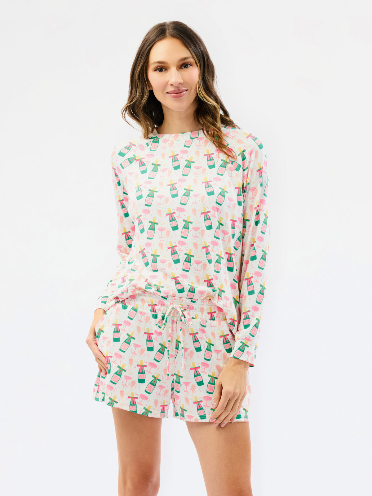 A woman modeling a matching long-sleeve top and shorts set with a colorful tropical drink print on a white background.