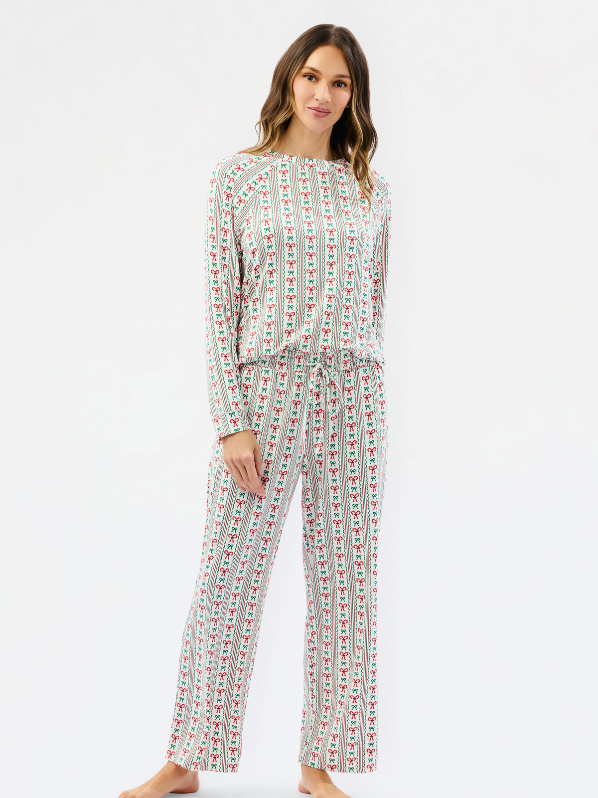 A woman modeling a matching long-sleeve top and wide-leg pants set with a vertical red and green pattern on a white background, photographed against a plain white studio backdrop.