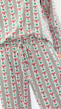 A person wearing a matching long-sleeve top and pants set with a festive Christmas print of red bows, green ribbons, and vertical stripes on a white background.