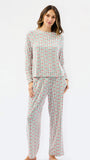 A woman modeling a matching two-piece pajama set with a long-sleeve top and wide-leg pants, featuring a vertical multicolor pattern of small illustrated figures on a light background, set against a plain white studio background.