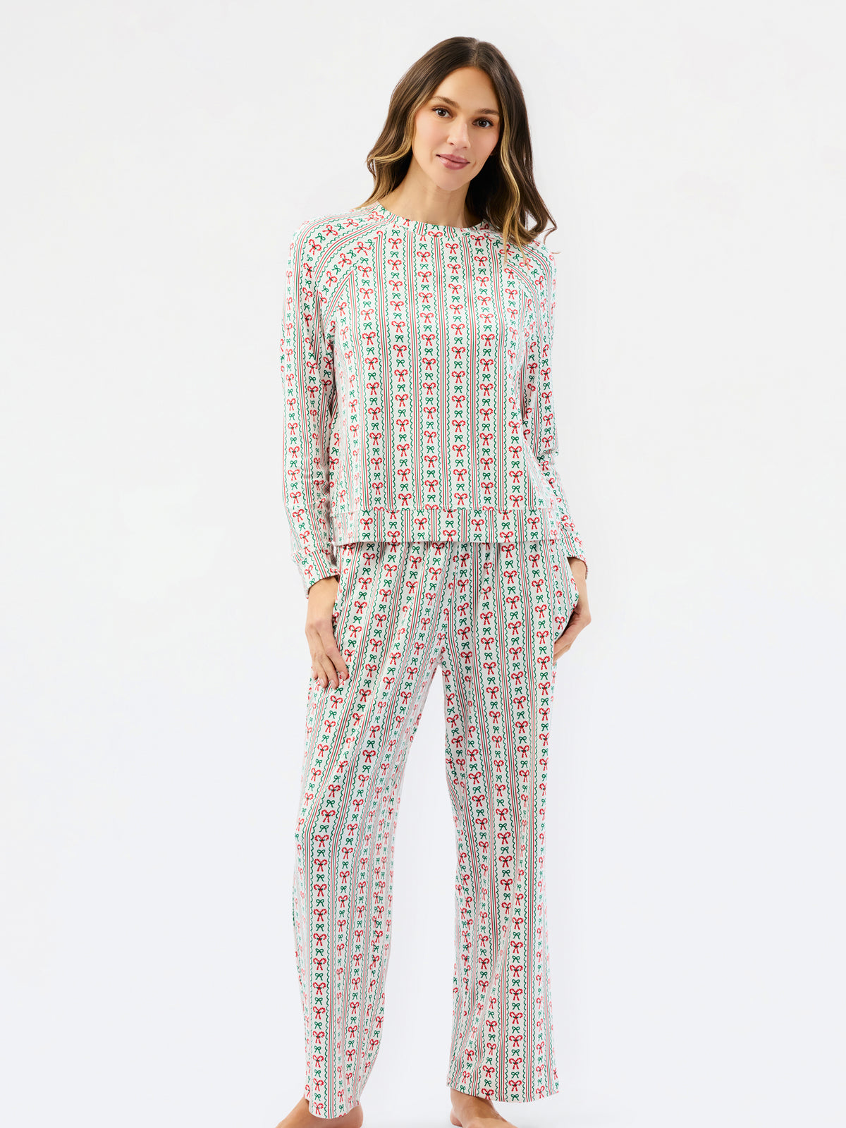 A woman modeling a matching two-piece pajama set with a long-sleeve top and wide-leg pants, featuring a vertical multicolor pattern of small illustrated figures on a light background, set against a plain white studio background.