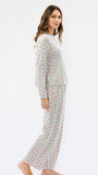 A woman modeling a matching two-piece pajama set with a white base and vertical red and green striped pattern, shown from a side profile against a plain white studio background.