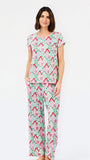 A woman modeling a two-piece pajama set featuring a light mint green base with a pink and red geometric pattern, set against a plain white studio background.