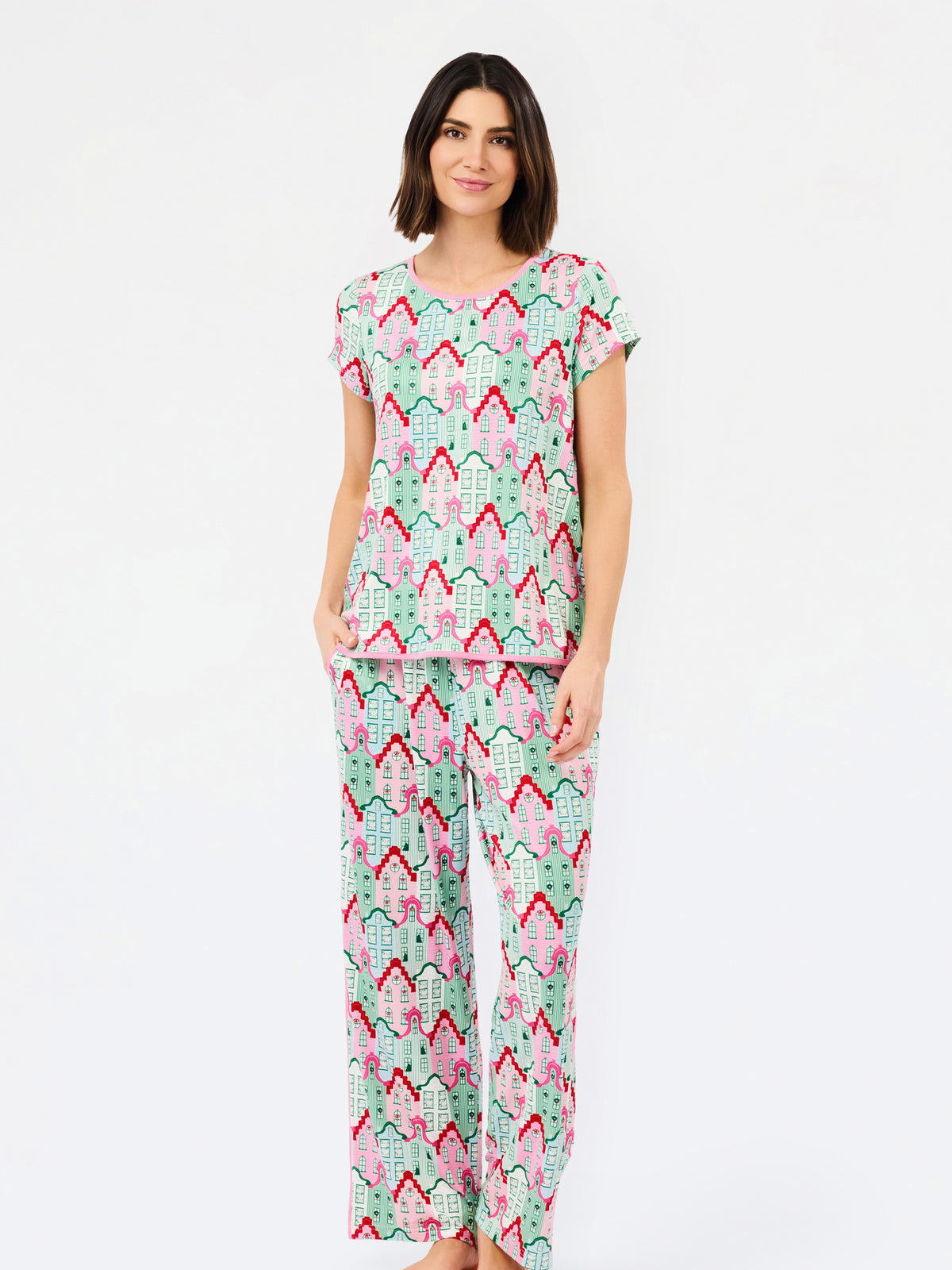 A woman modeling a two-piece pajama set featuring a light mint green base with a pink and red geometric pattern, set against a plain white studio background.