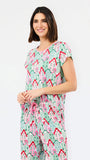 A woman modeling a matching short-sleeve top and wide-leg pants set in a mint green, pink, and red geometric pattern against a plain white background.