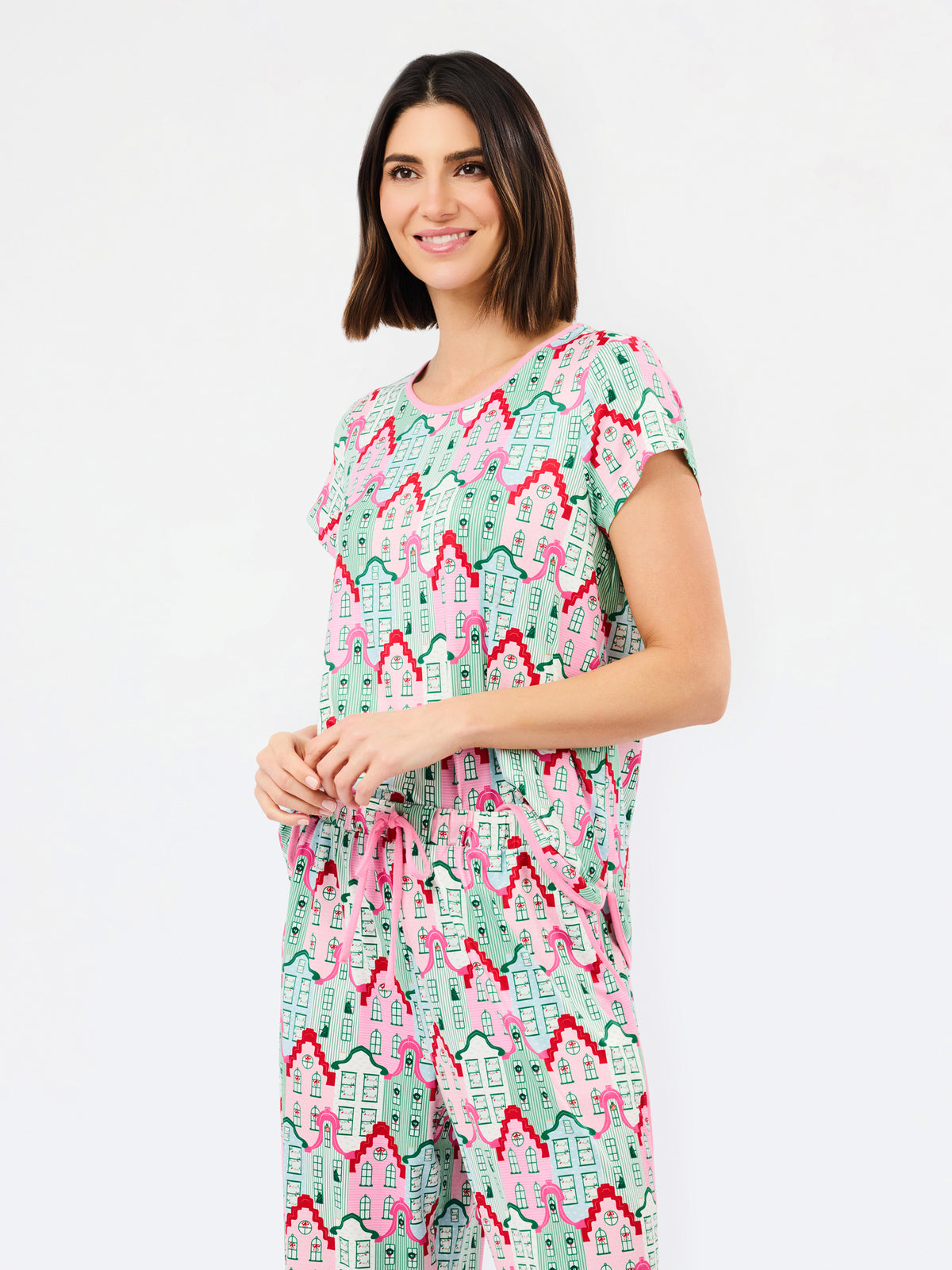 A woman modeling a matching short-sleeve top and wide-leg pants set in a mint green, pink, and red geometric pattern against a plain white background.