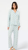 A woman modeling a two-piece long-sleeve pajama set with a light blue and white pineapple print, standing against a plain white studio background.