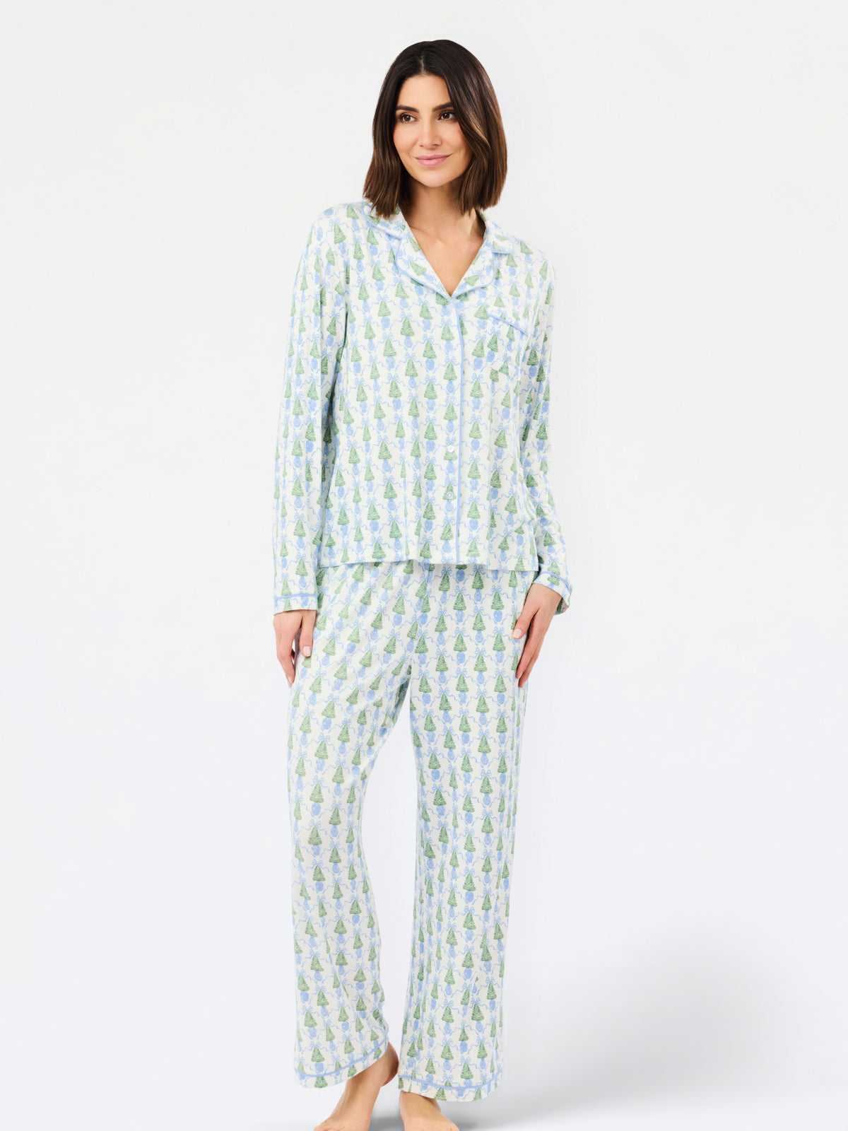 A woman modeling a two-piece long-sleeve pajama set with a light blue and white pineapple print, standing against a plain white studio background.