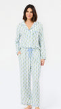 A woman modeling a matching long-sleeve pajama set with a light blue and green pineapple print, featuring a button-up top and matching pants with a drawstring waist, against a plain white background.