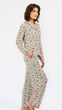 A woman modeling a two-piece pajama set featuring a long-sleeve button-up top and matching pants, both printed with a green, pink, and red strawberry pattern on a white background.