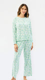 A woman modeling a two-piece pajama set with a light green and white abstract pattern, consisting of a long-sleeve top and matching pants, against a plain white studio background.