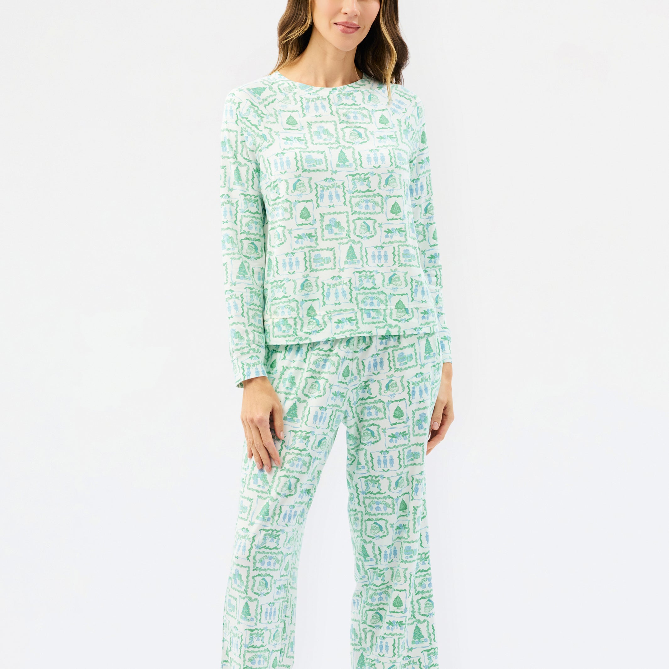 A woman modeling a two-piece pajama set with a light green and white abstract pattern, consisting of a long-sleeve top and matching pants, against a plain white studio background.