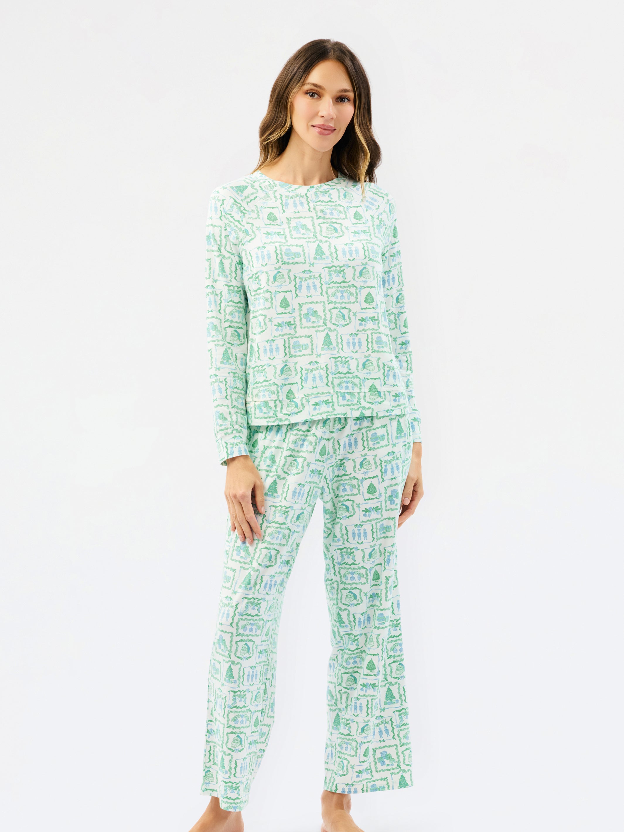 A woman modeling a two-piece pajama set with a light green and white abstract pattern, consisting of a long-sleeve top and matching pants, against a plain white studio background.