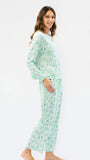 A woman modeling a two-piece long-sleeve pajama set with a green and white geometric pattern, shown from a side profile against a plain white studio background.
