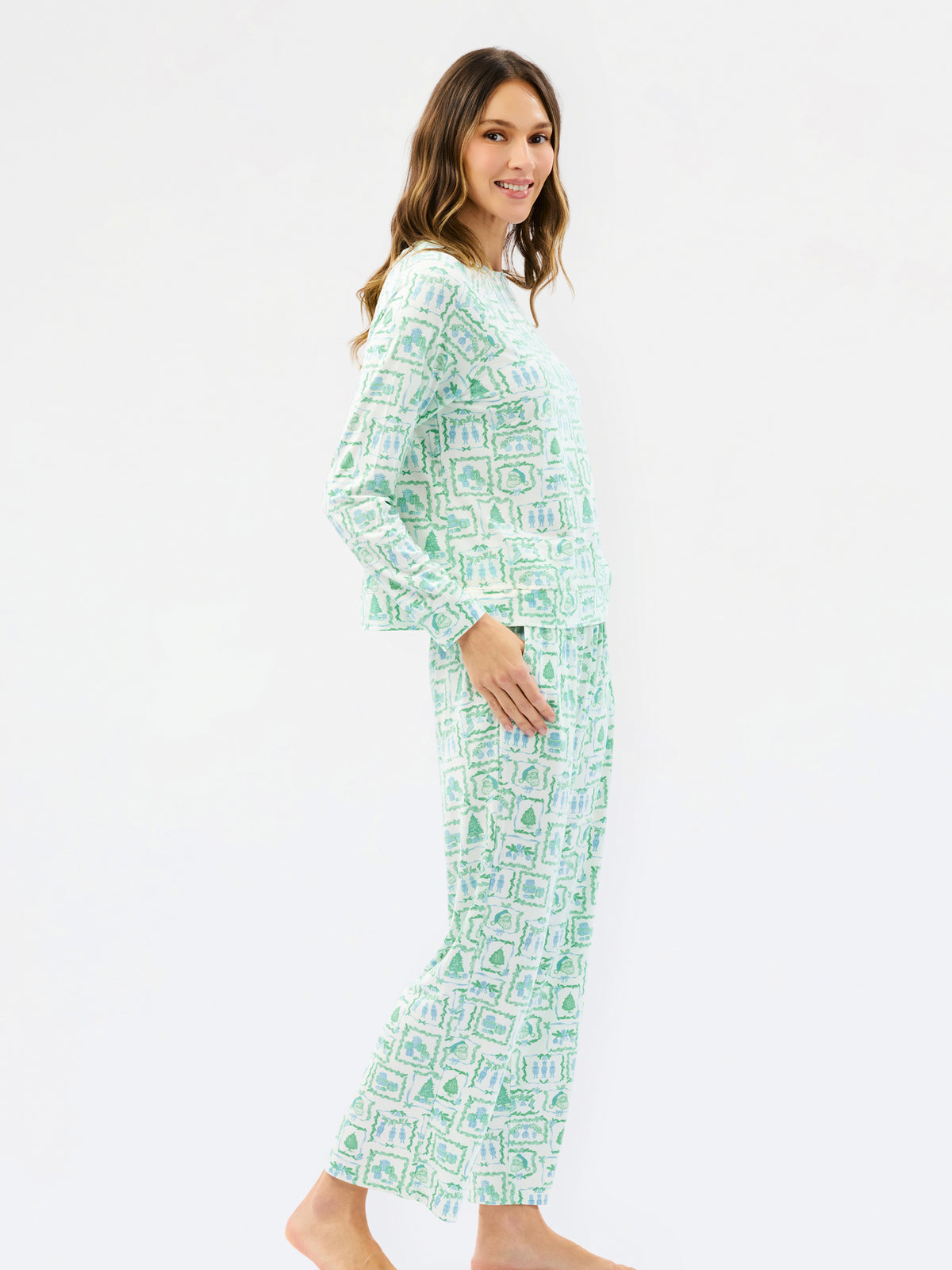 A woman modeling a two-piece long-sleeve pajama set with a green and white geometric pattern, shown from a side profile against a plain white studio background.