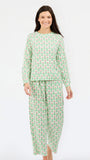A woman modeling a two-piece pajama set featuring a light green and white pattern of small cartoon characters, set against a plain white studio background.