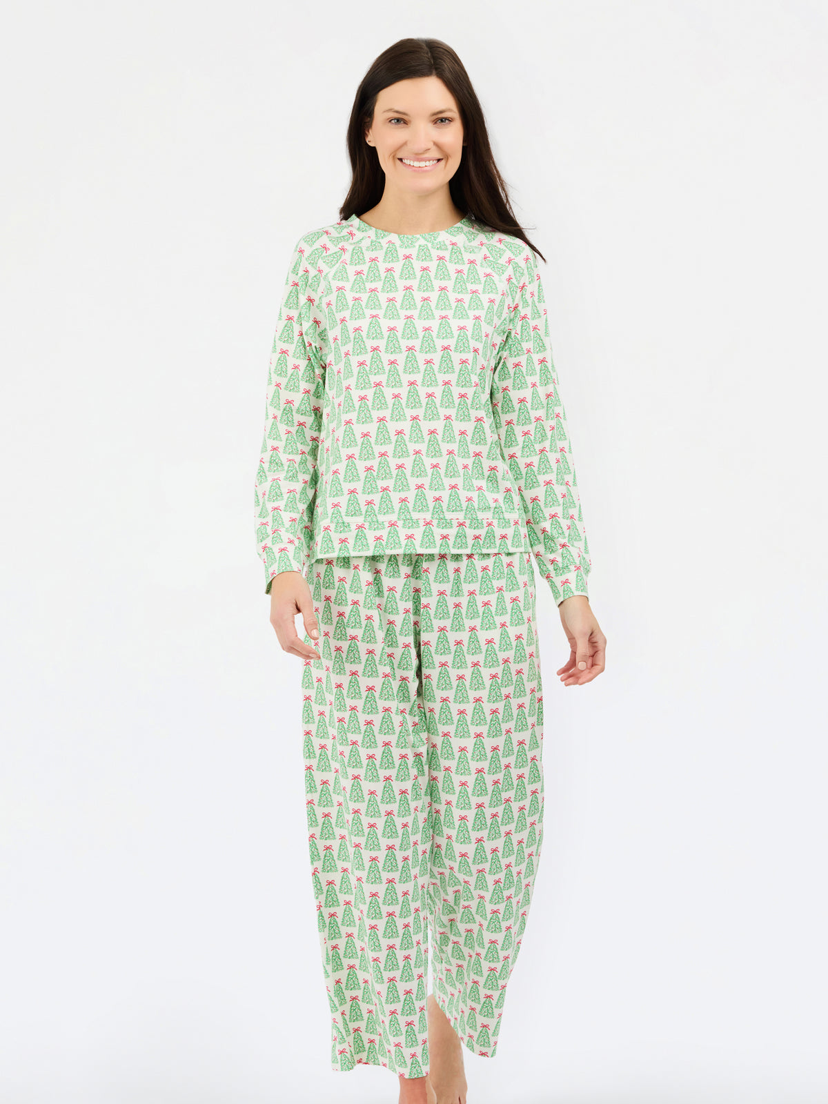 A woman modeling a two-piece pajama set featuring a light green and white pattern of small cartoon characters, set against a plain white studio background.
