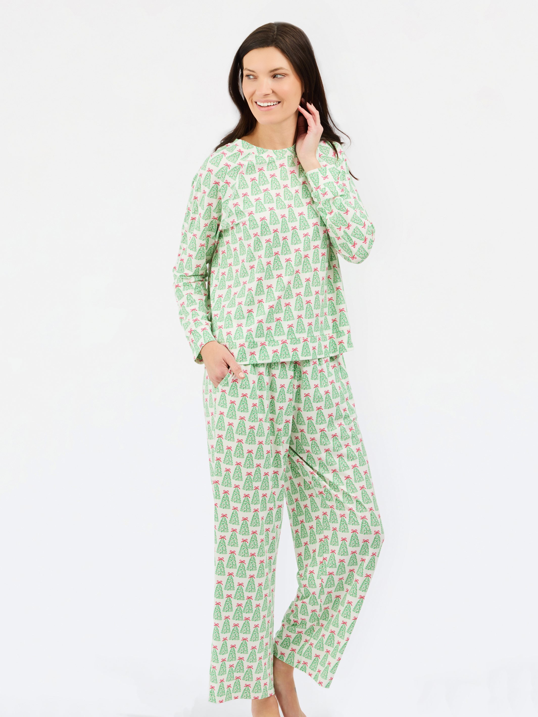 A woman modeling a two-piece pajama set with a light green and white pattern of small illustrated figures, photographed against a plain white studio background.