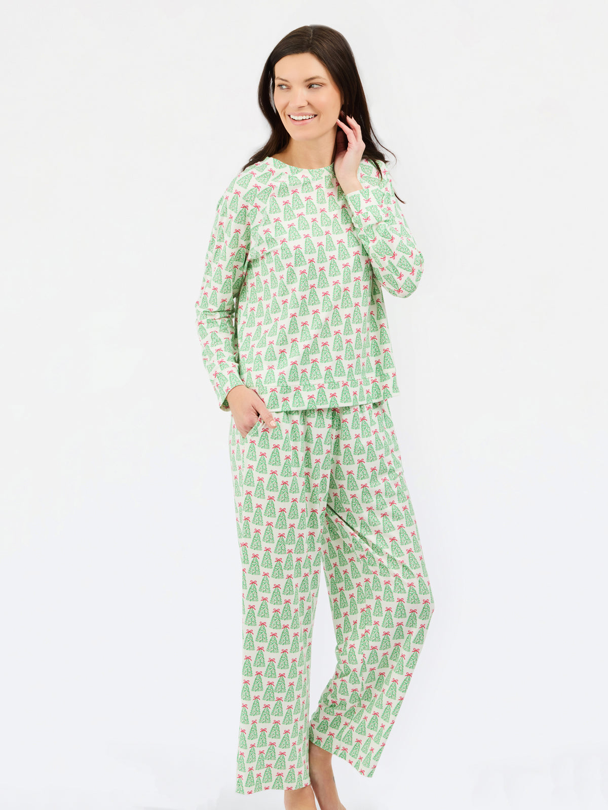 A woman modeling a two-piece pajama set with a light green and white pattern of small illustrated figures, photographed against a plain white studio background.