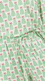 A close-up of a light-colored fabric garment with an all-over Christmas tree print. The pattern features green pine trees with red bows, and a matching drawstring waistband is visible at the center.
