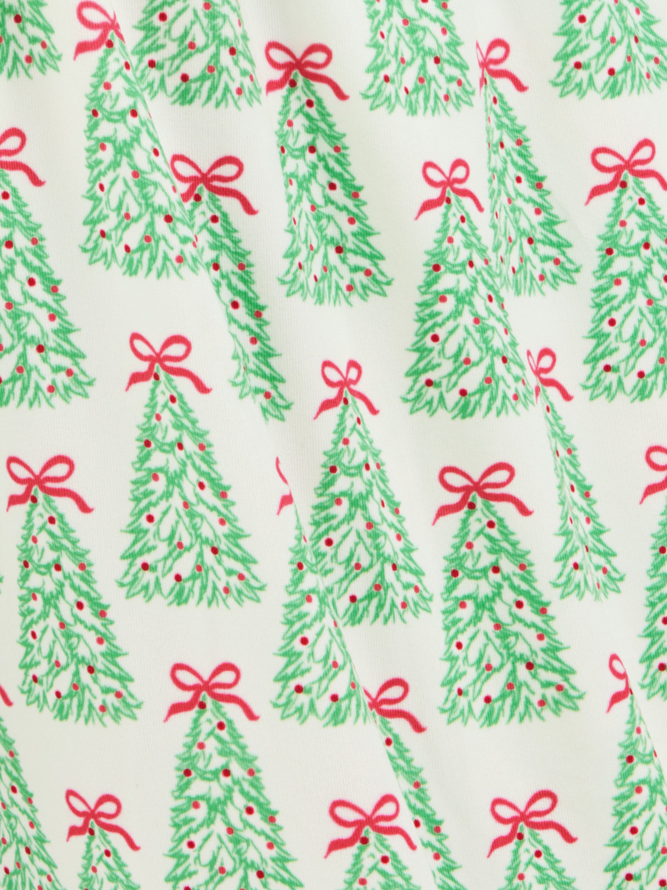 A close-up of a fabric or wallpaper pattern featuring green Christmas tree silhouettes with small red ornaments and red bows on an off-white background.