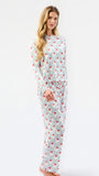 A woman modeling a two-piece long-sleeve pajama set with a white base, thin vertical gray stripes, and a scattered red heart pattern, set against a plain white studio background.