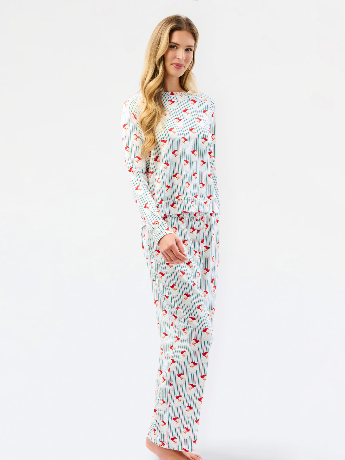 A woman modeling a two-piece long-sleeve pajama set with a white base, thin vertical gray stripes, and a scattered red heart pattern, set against a plain white studio background.