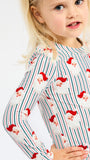 A young girl wearing a long-sleeve white top with red and blue vertical stripes and a Santa Claus face pattern, photographed against a plain white background.