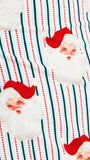 A close-up of a festive fabric print featuring Santa Claus faces with white fluffy beards and red hats, set against a background of green and red vertical stripes.