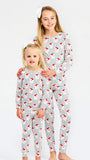 Two young girls modeling matching long-sleeve pajama sets with a white base, thin blue pinstripes, and a red bird print, posed against a plain white studio background.