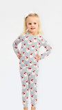 A young blonde girl wearing a long-sleeve pajama set with a blue and white pinstripe pattern and red Santa Claus motifs, standing against a plain white background.