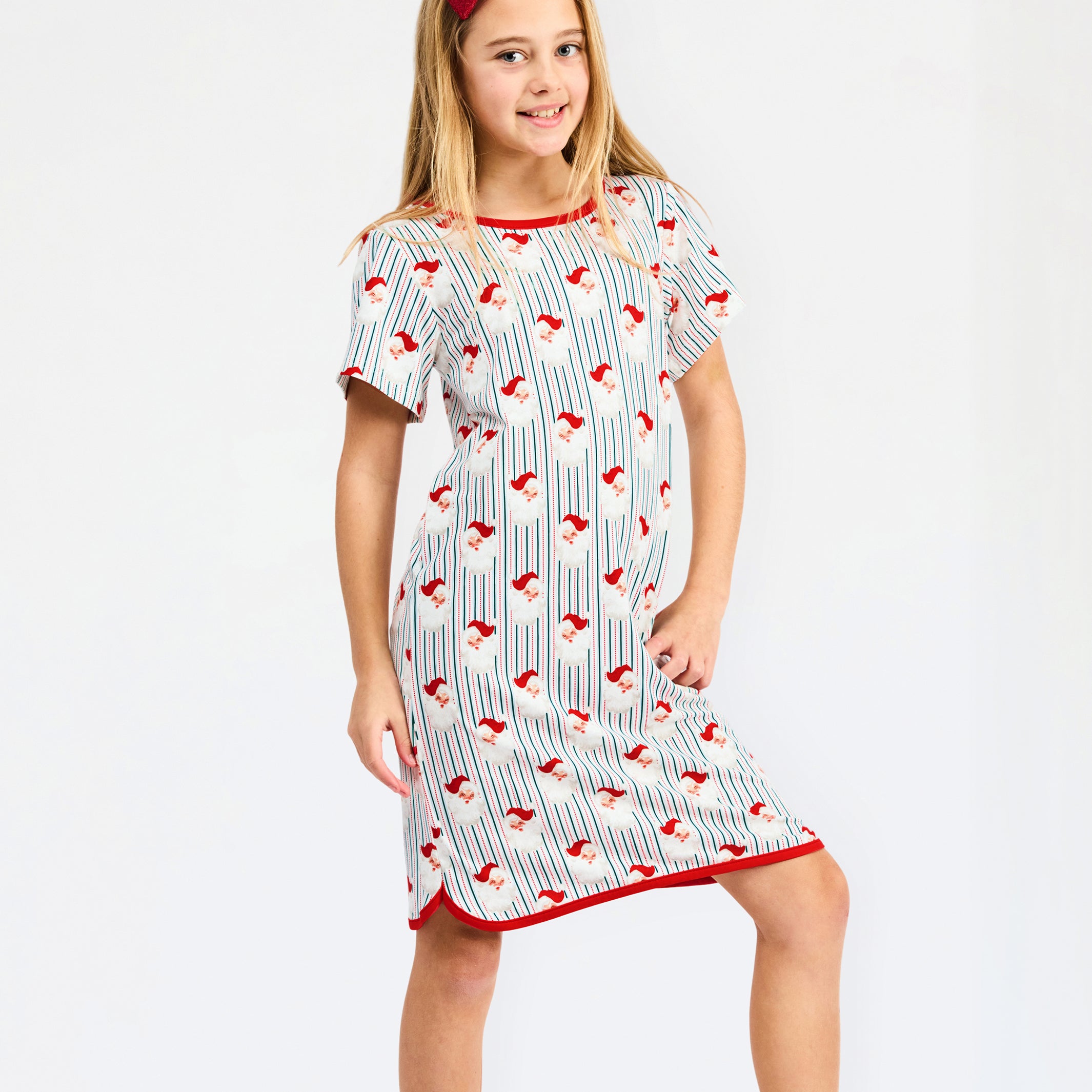 A young girl modeling a short-sleeve nightgown with a white base, red trim, and a repeating pattern of red birds on thin vertical blue stripes, set against a plain white studio background.