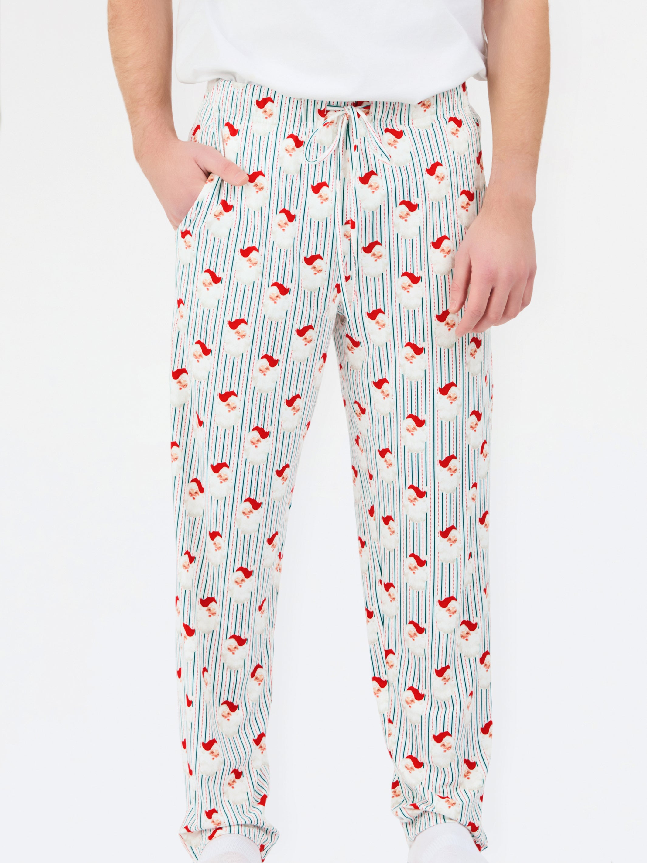 A person wearing white drawstring pants with a vertical blue stripe pattern and small red Santa hats printed throughout, paired with a white top against a plain white background.