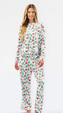 A woman modeling a matching long-sleeve top and pants pajama set with a festive Christmas print of Santa Claus, sleighs, and green trees on a white background.