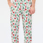 A person wearing holiday-themed lounge pants with an all-over Christmas print featuring Santa Claus, reindeer, trees, and sleighs on a white background.
