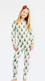 A young girl with blonde hair and a red bow headband is wearing a two-piece long-sleeve pajama set with a Christmas tree pattern, standing against a plain white background.