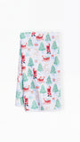A folded white kitchen towel featuring a festive Christmas print with Santa Claus, reindeer, Christmas trees, and gifts on a clean white background.
