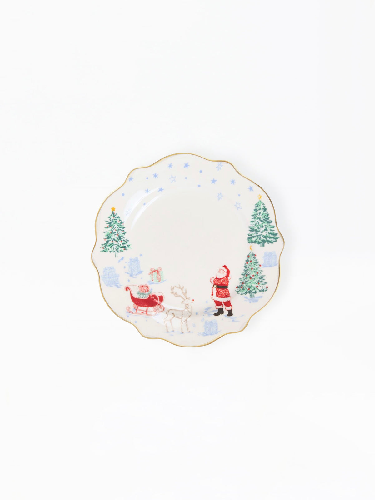 A scalloped ceramic plate with a festive Christmas design, featuring Santa Claus, a reindeer, and snow-covered pine trees on a white background with a thin gold rim.