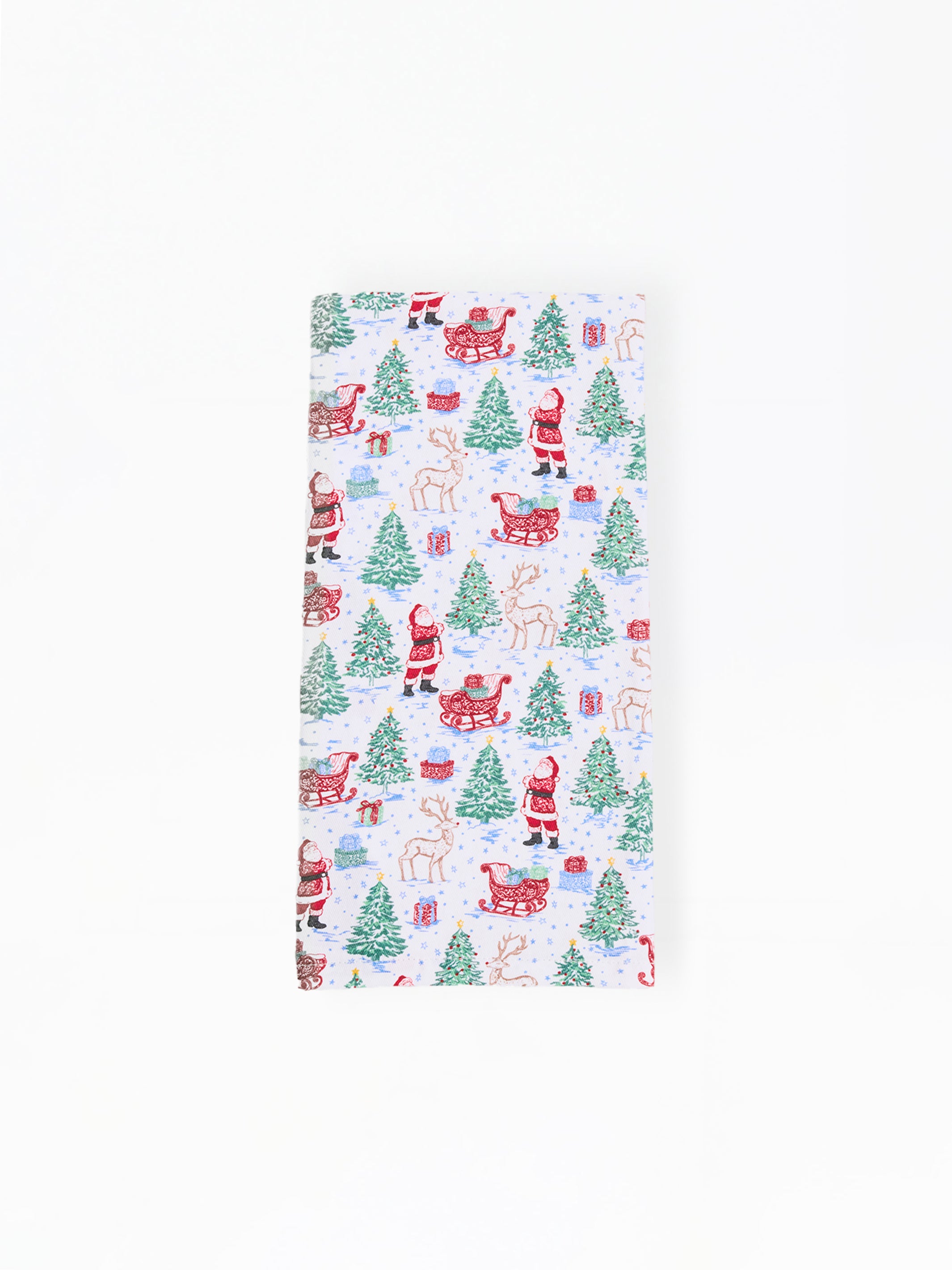 A rectangular white fabric item, likely a napkin or tea towel, featuring a repeating Christmas pattern of Santa Claus, reindeer, sleighs, and green Christmas trees.